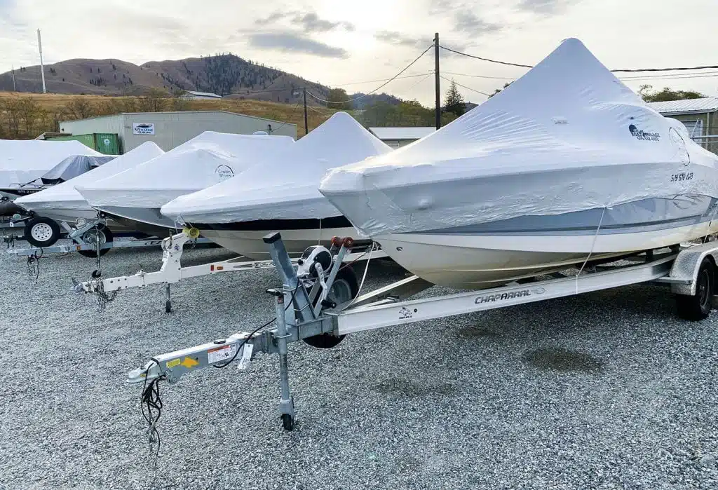 row of covered boats on trailers outdoors